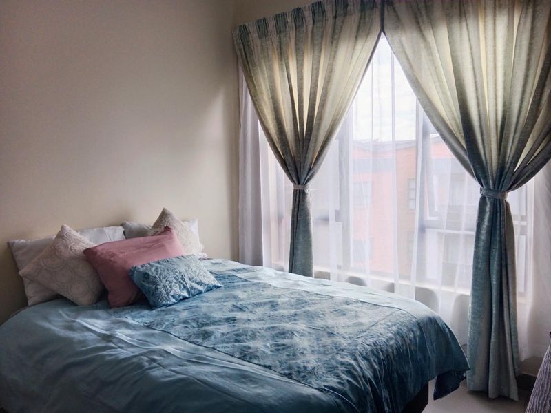 A cozy bedroom featuring a large window that allows for natural light, creating a bright and inviting atmosphere.