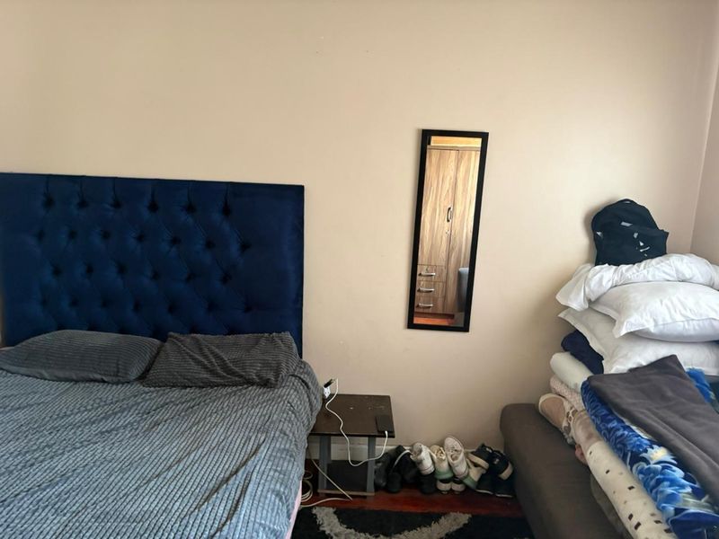 A standard bedroom featuring neutral wall finishes and wooden flooring, providing a functional space for rest.