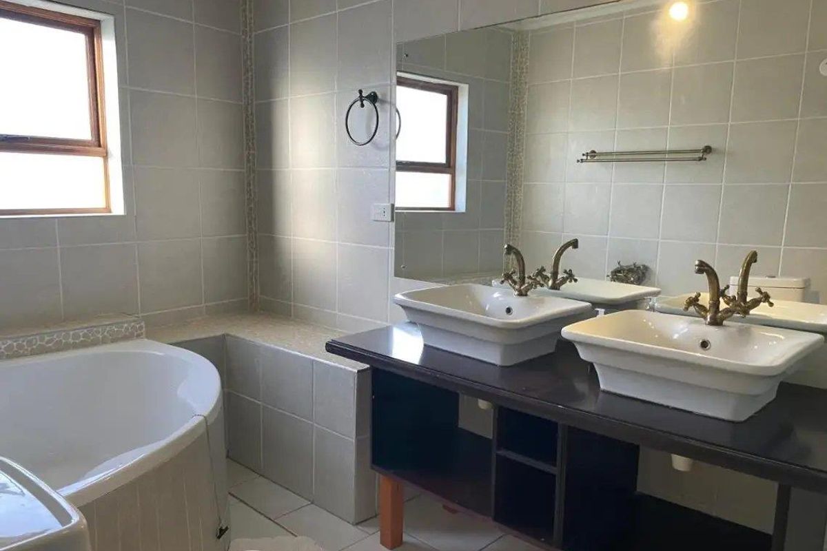 A functional bathroom featuring a double vanity with vessel sinks, a corner bathtub, and tiled walls.