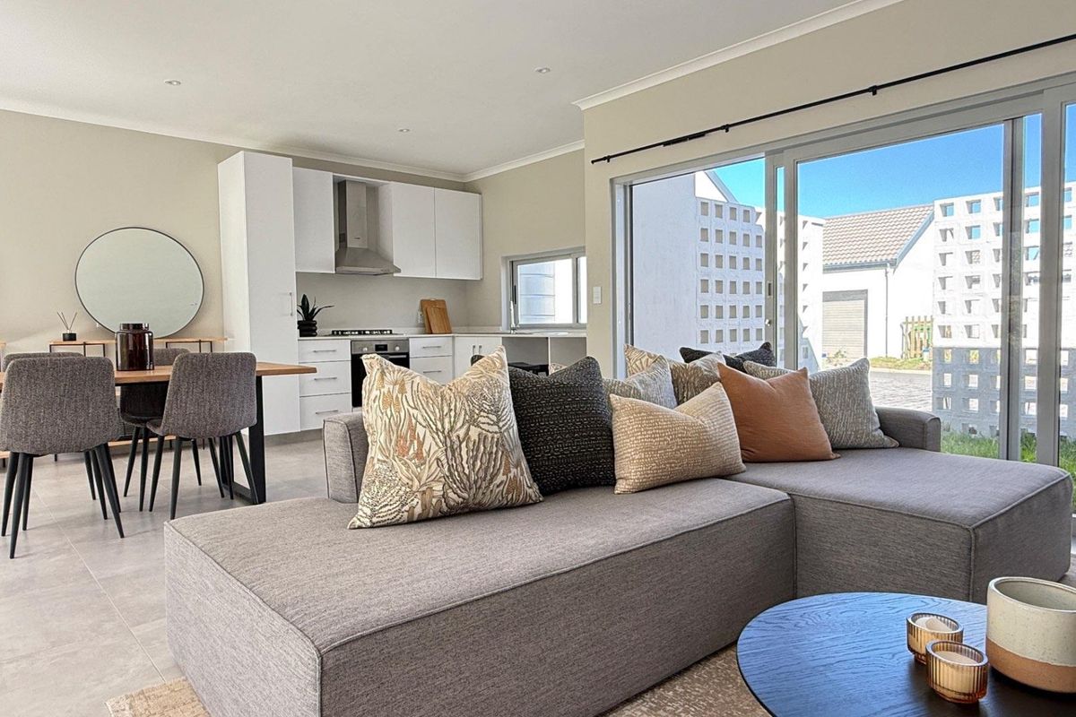 Modern open-plan living and kitchen area featuring sleek white cabinetry, integrated appliances, tiled floors, and large sliding doors opening to the exterior.