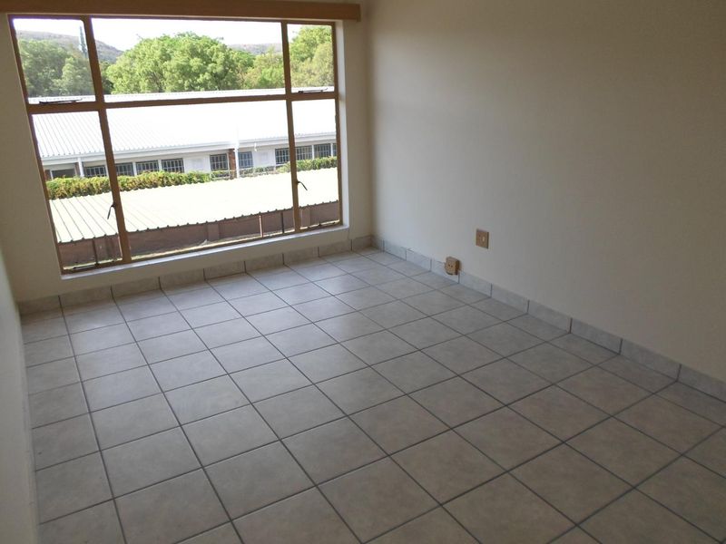 A bright, empty bedroom featuring neutral tiled flooring, large windows providing natural light, and clean wall finishes, ready for personalization.