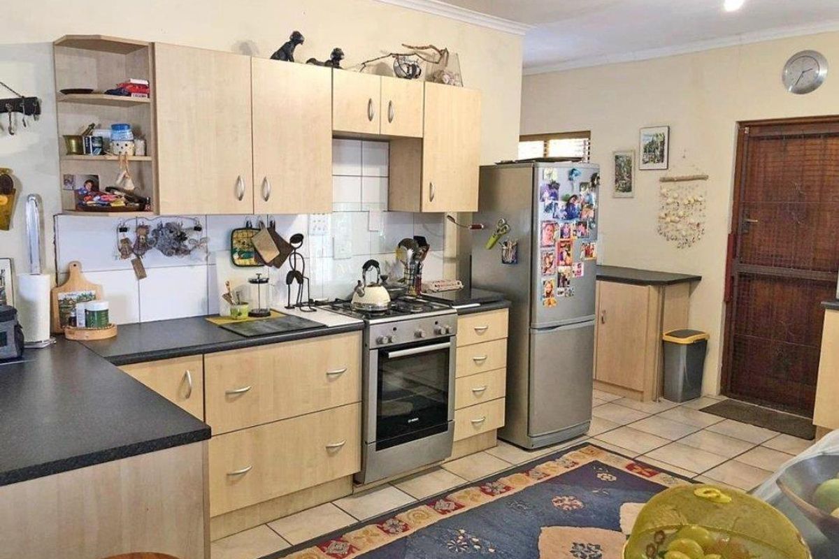 Functional kitchen featuring light wood-tone cabinetry, dark laminate countertops, a gas stove with oven, and tiled flooring.