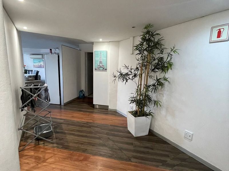 A well-lit hallway featuring modern dual-tone laminate flooring and recessed ceiling lighting, providing a clean transition between living spaces.
