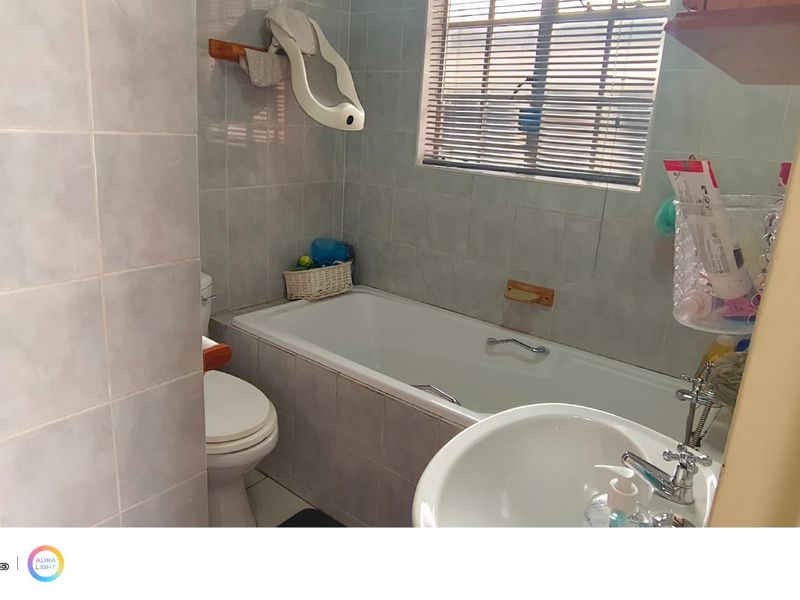 A functional bathroom featuring a bathtub, toilet, and pedestal basin with tiled wall finishes and window blinds.