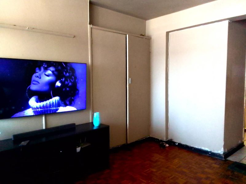 Bedroom featuring parquet flooring and built-in cupboards, requiring cosmetic updates to the walls and skirting boards.
