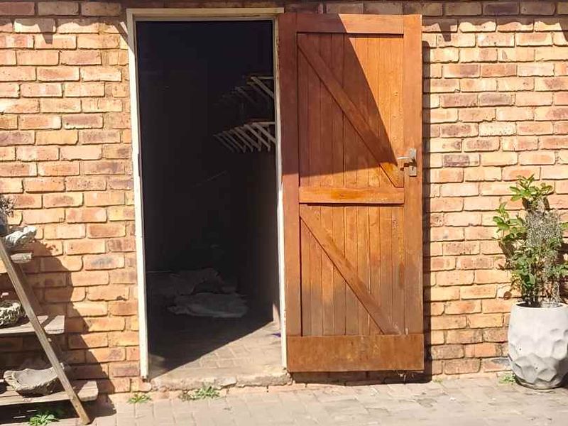 Rear exterior view of a townhouse featuring a brick facade, tiled roof, and a timber door leading to an outdoor paved area.