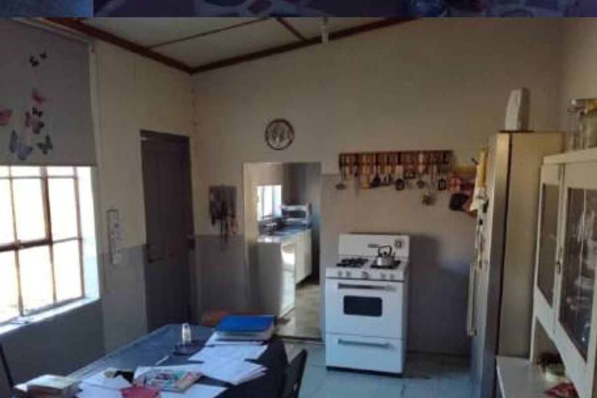 A functional kitchen area featuring a freestanding stove, tiled flooring, and an adjacent scullery or prep space with natural light.