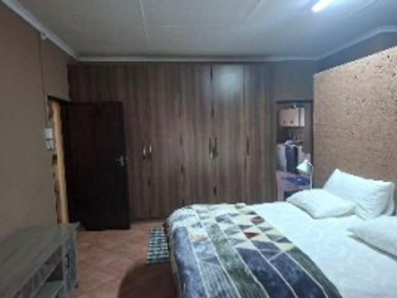 A bedroom featuring built-in wooden cupboards, tiled flooring, and a coved ceiling, offering functional storage space.