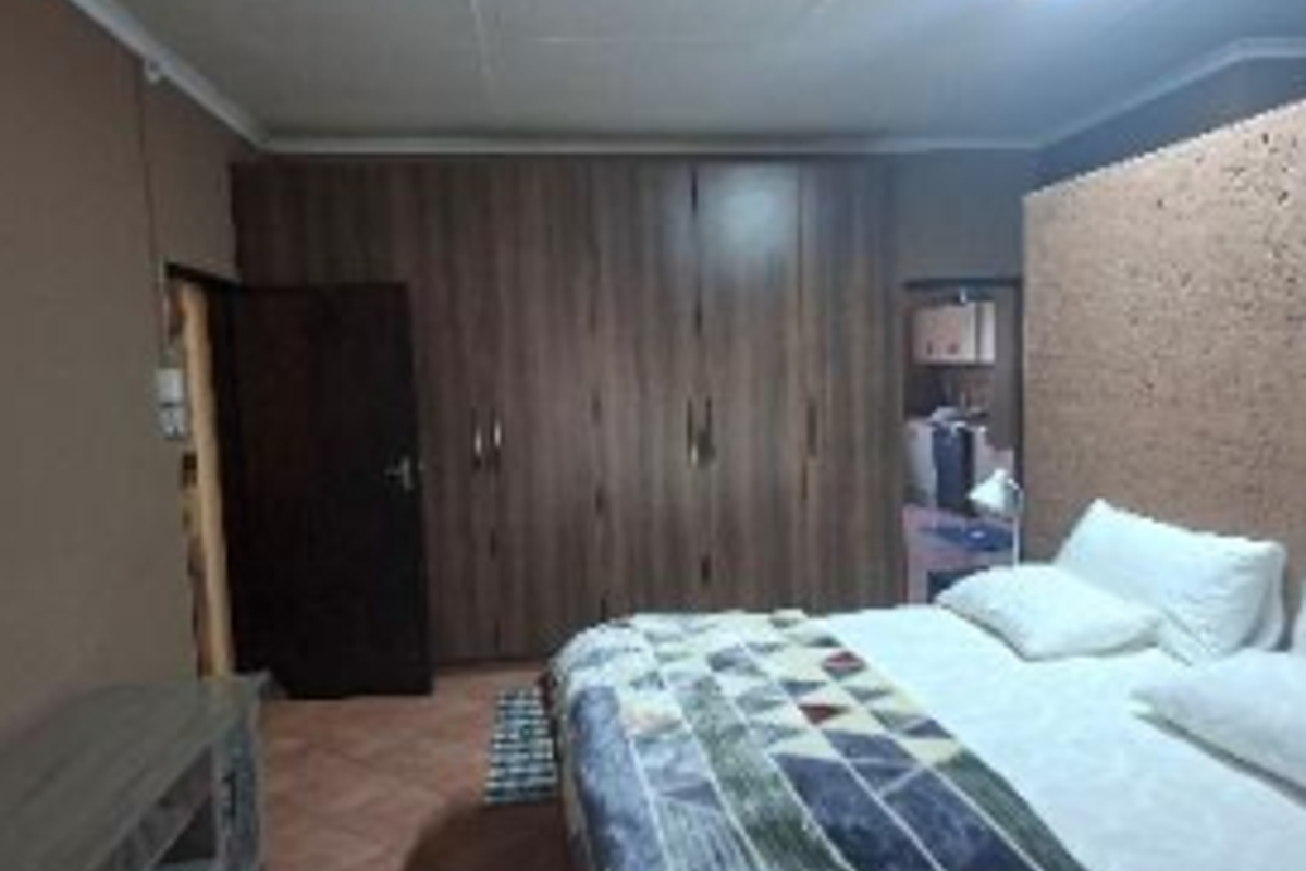A bedroom featuring built-in wooden cupboards, tiled flooring, and a coved ceiling, offering functional storage space.
