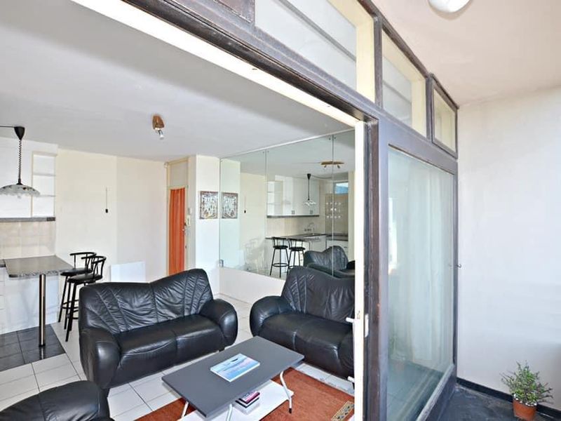 Open plan living and kitchen area featuring tiled floors, a mirrored wall, and sliding glass doors leading to an outdoor space.