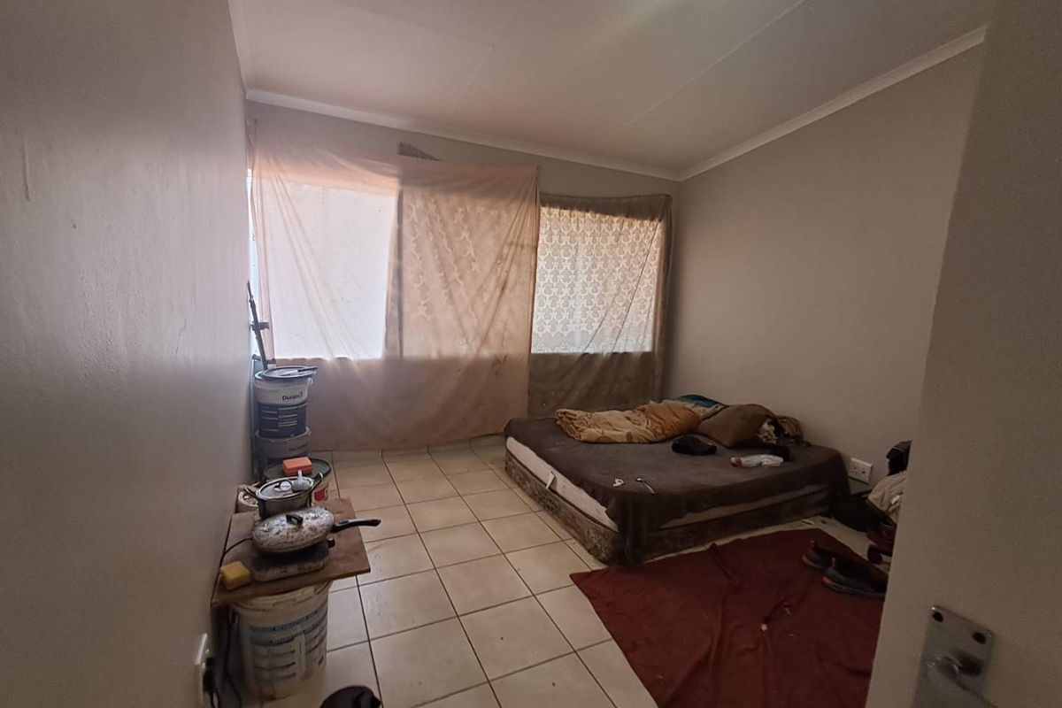 A bedroom featuring tiled flooring and a large window, currently requiring maintenance and cosmetic updates to improve its overall condition and appeal.