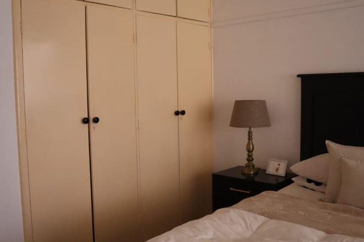 A bedroom featuring floor-to-ceiling built-in storage cupboards with a neutral finish.