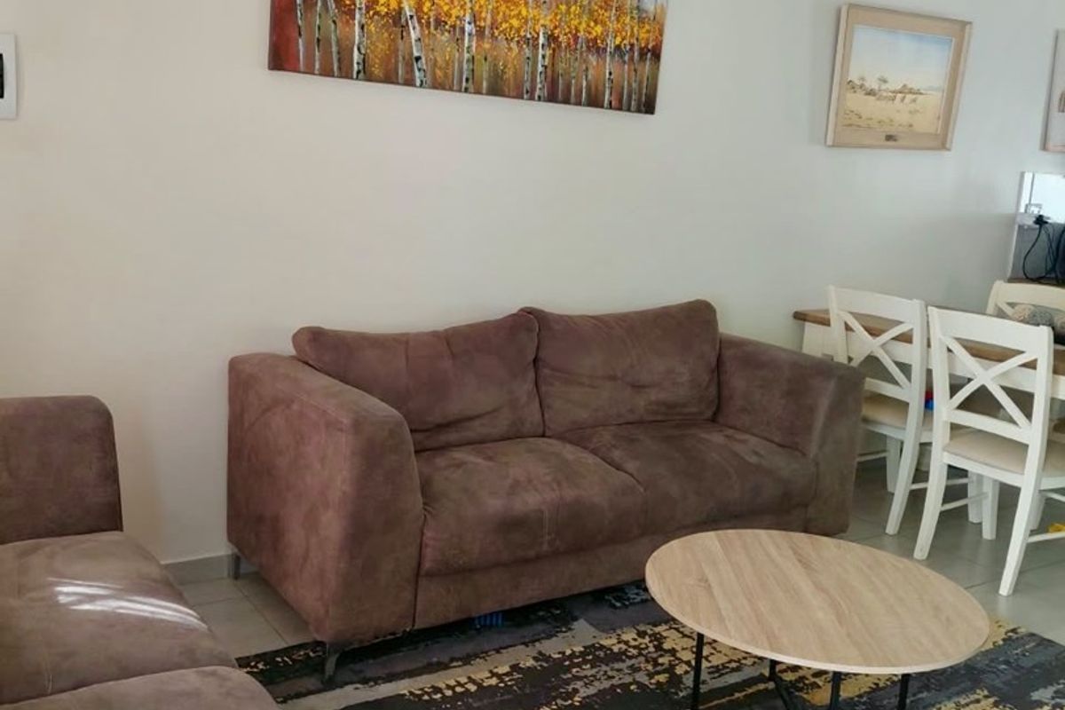 A well-maintained living room featuring neutral wall tones, tiled flooring, and decorative coving, providing a comfortable and functional space.