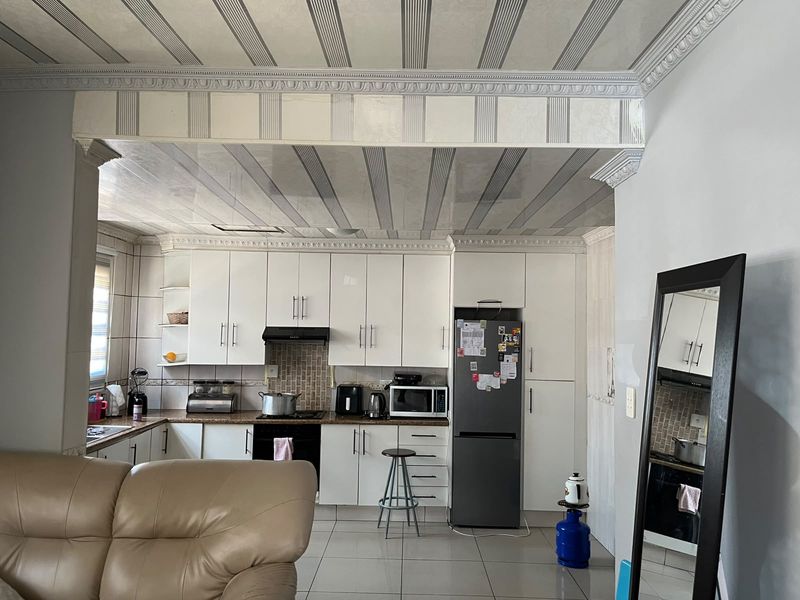 A functional kitchen featuring white cabinetry, tiled backsplash, and distinctive decorative ceiling paneling, offering a practical layout for daily meal preparation.