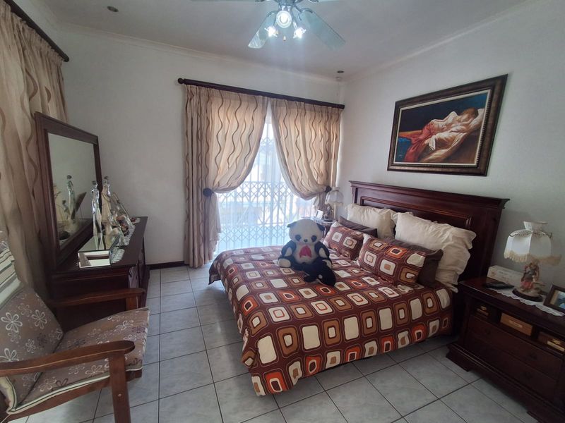 A bedroom featuring tiled flooring, a ceiling fan, and a sliding glass door with an integrated security gate.