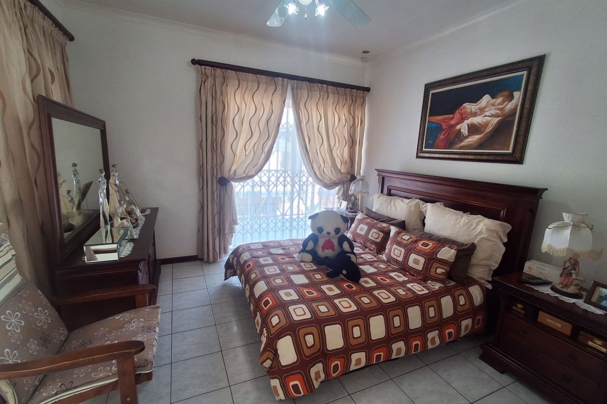 A bedroom featuring tiled flooring, a ceiling fan, and a sliding glass door with an integrated security gate.