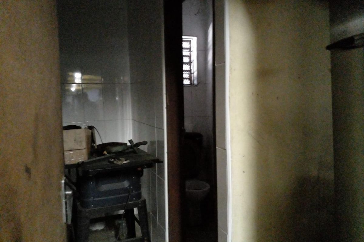 A small, dimly lit bathroom space featuring tiled walls and a toilet, currently in need of maintenance and cosmetic updates.