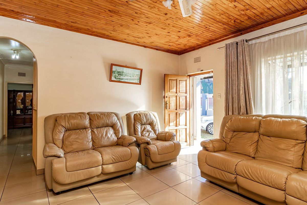 Spacious living room featuring ceramic floor tiles, a warm timber tongue and groove ceiling, and an arched entryway leading to the hallway.