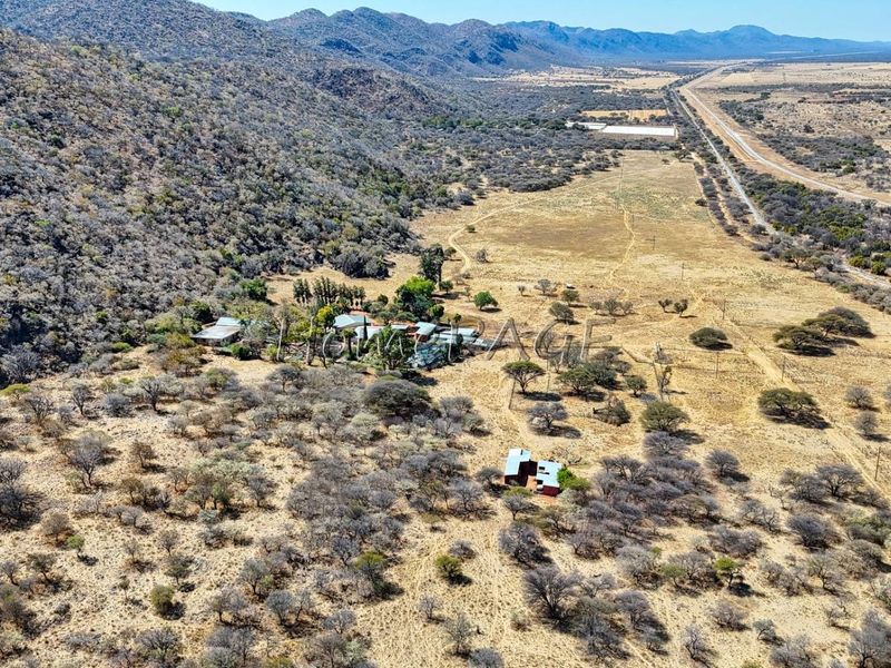 Aerial view of a large rural small holding property featuring expansive natural landscape, outbuildings, and access to main road infrastructure.