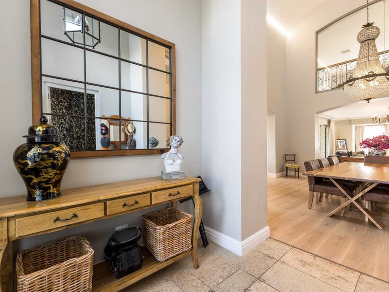 Elegant entrance foyer featuring stone tile flooring, transitioning into a spacious open-plan living area with hardwood floors and a grand chandelier.