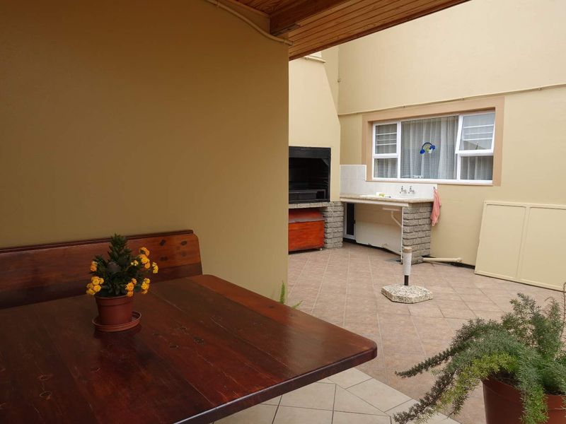 Covered patio area featuring a built-in braai, tiled flooring, and a timber ceiling, providing a functional outdoor entertainment space.
