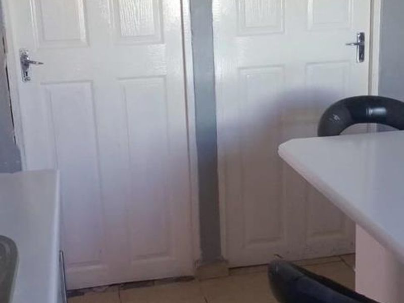 A functional kitchen area featuring tiled flooring, a built-in breakfast bar, and dual panelled interior doors.