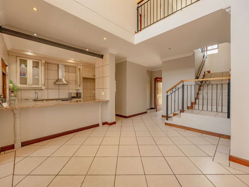 Spacious open-plan living area featuring a kitchen with granite countertops, tiled flooring, and a staircase leading to the upper level.