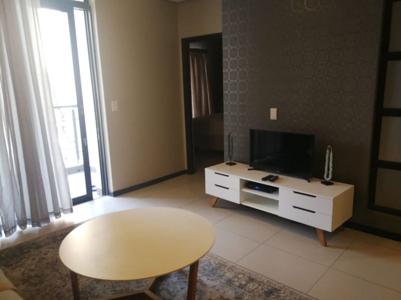A living room featuring tiled flooring, a textured feature wall, and a sliding glass door providing access to an outdoor area.