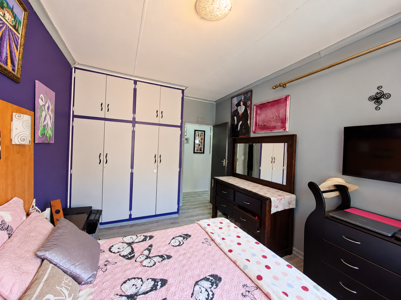 A bedroom featuring built-in wardrobes, laminate flooring, and a ceiling light fixture.