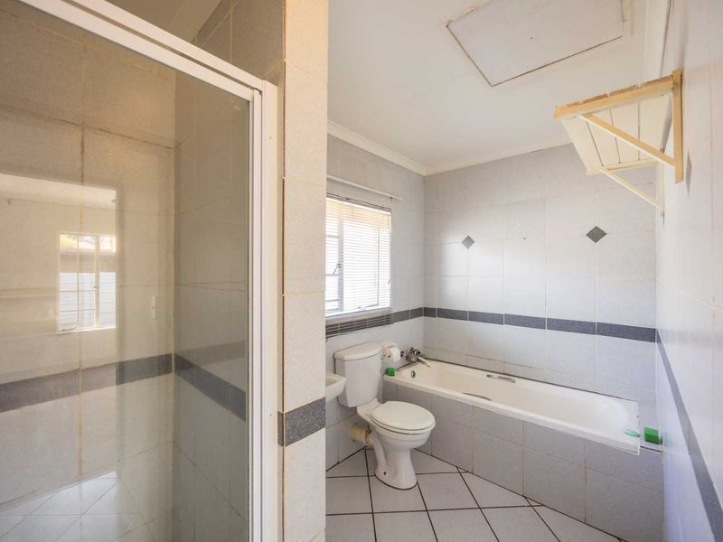 A functional bathroom featuring a separate shower enclosure, bathtub, toilet, and tiled finishes throughout, offering a clean and practical layout.