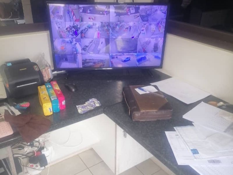 A functional office workspace featuring a built-in desk and tiled flooring, currently utilized for security monitoring.