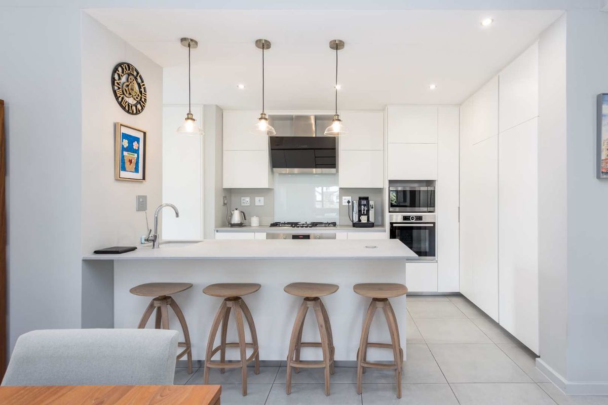 Modern kitchen featuring a central island with breakfast bar, integrated appliances, sleek handleless cabinetry, and contemporary pendant lighting.