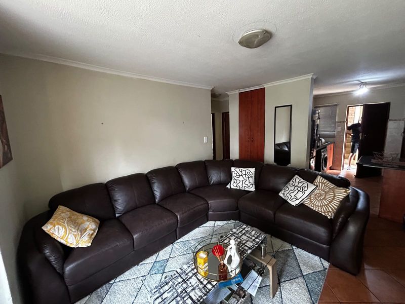 Open plan living area featuring tiled flooring and built-in storage, with a direct view into the kitchen and exterior entrance.