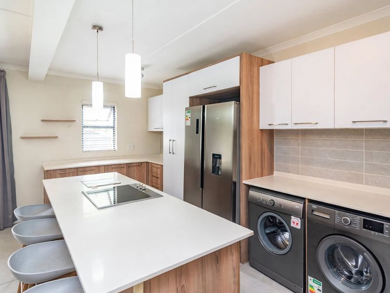 Modern kitchen featuring a central island with a built-in hob, sleek cabinetry, stone countertops, and integrated appliance housing in a clean, contemporary finish.