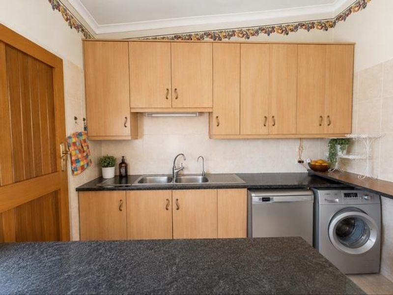 Functional scullery featuring laminate cabinetry, granite countertops, double bowl sink, and integrated laundry appliances, providing efficient utility space.