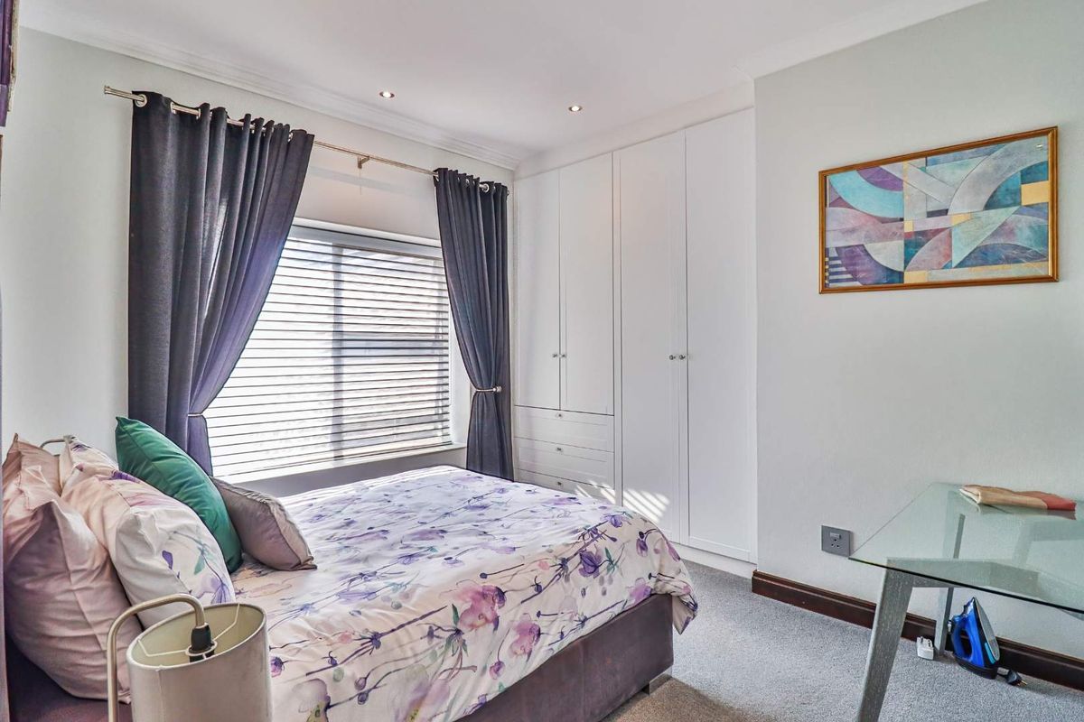 A well-maintained bedroom featuring built-in floor-to-ceiling wardrobes, recessed ceiling lighting, and neutral carpeting.
