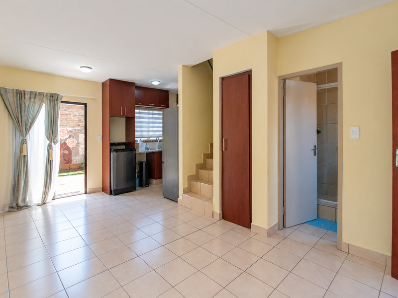 Open plan living area featuring tiled flooring, built-in kitchen cabinetry, and direct access to an outdoor patio area.