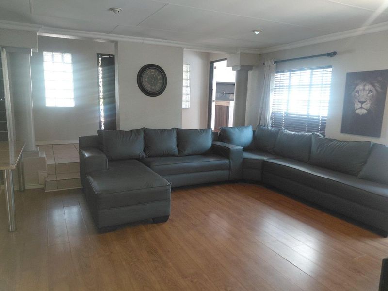 Spacious living room featuring laminate flooring, recessed lighting, and unique glass block window accents, providing a bright and functional living space.