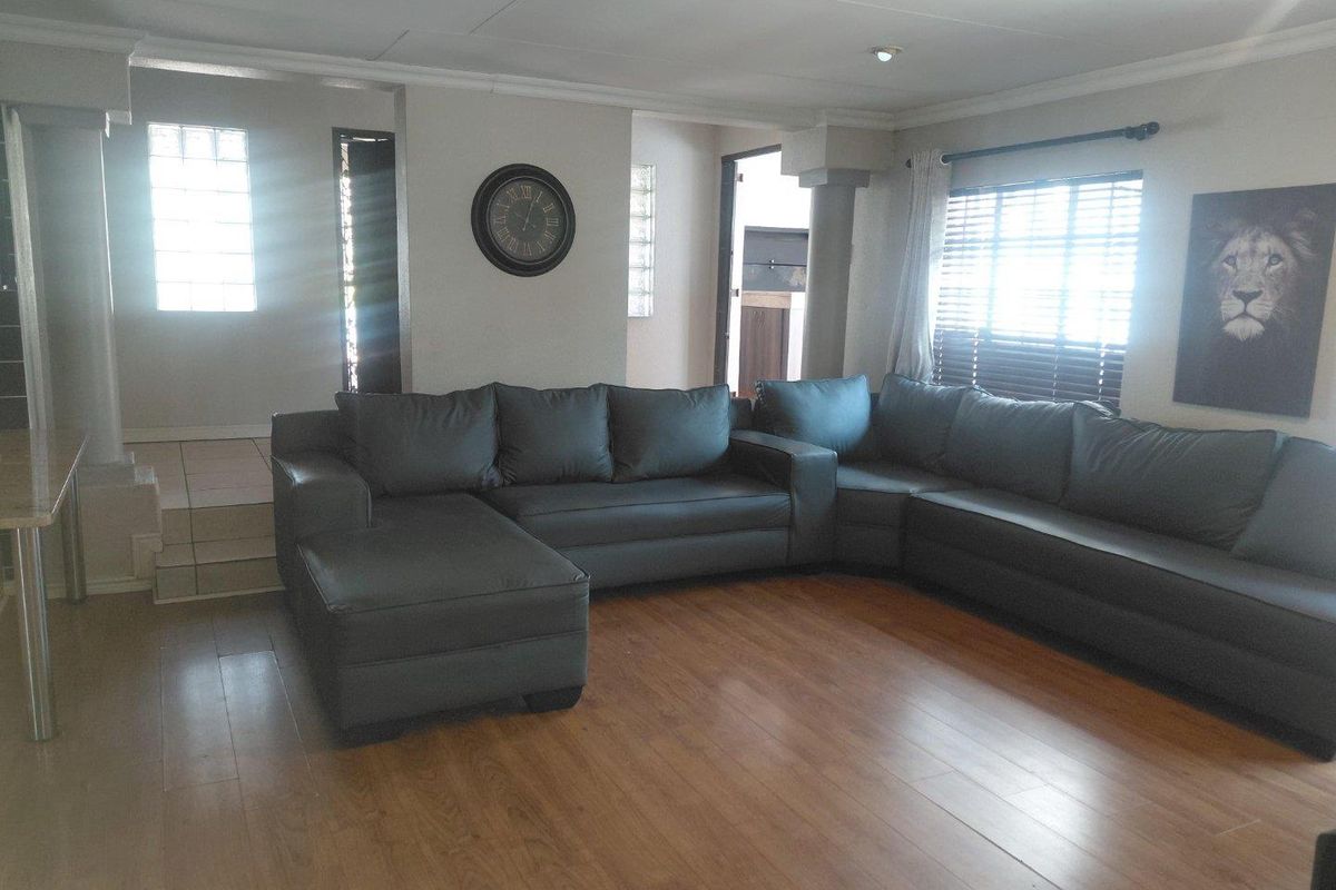 Spacious living room featuring laminate flooring, recessed lighting, and unique glass block window accents, providing a bright and functional living space.
