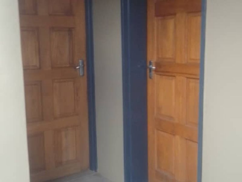 A simple interior hallway featuring two wooden panel doors and concrete flooring.