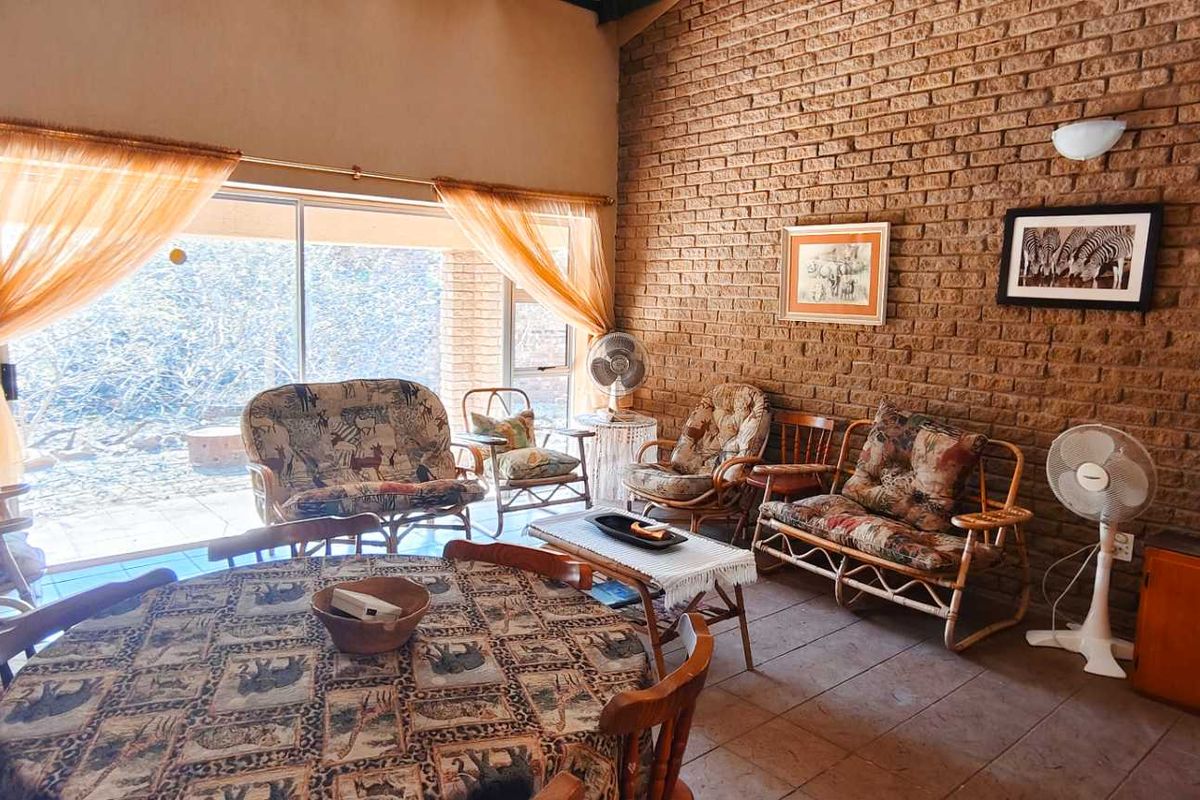 Spacious living area featuring a prominent exposed brick wall, vaulted ceiling, and large sliding glass doors providing access to the outdoor space.