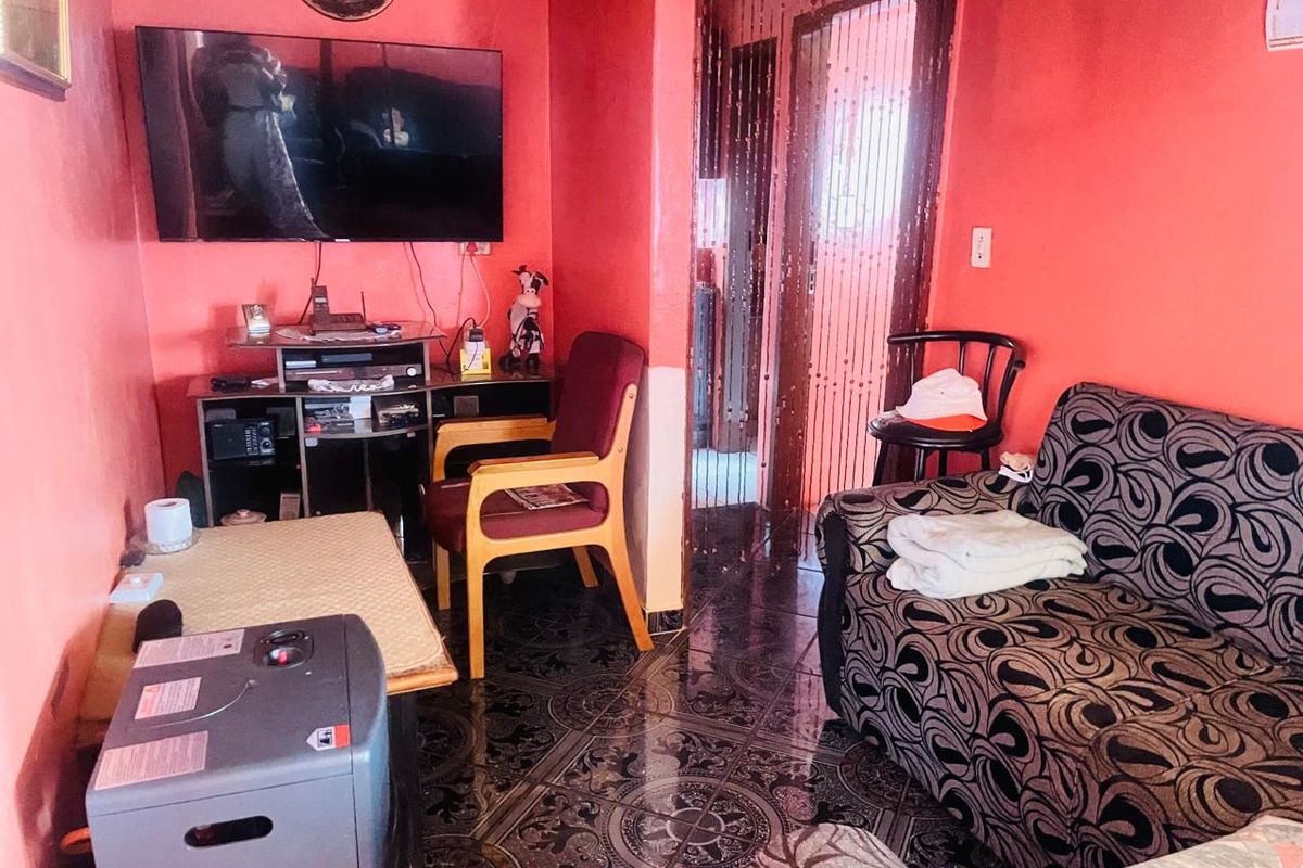 A living room featuring bold red walls and patterned floor tiles, providing a compact space for relaxation.