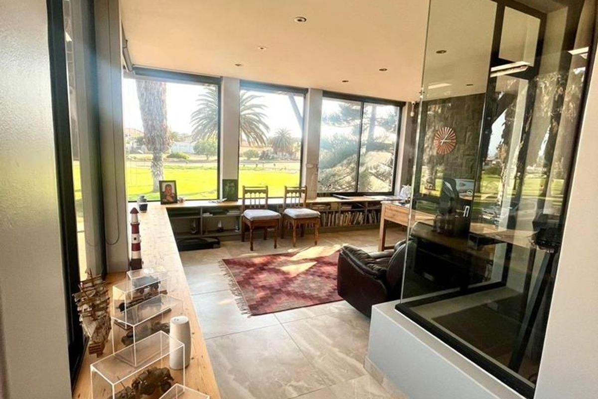 Bright living area featuring large floor-to-ceiling windows, tiled flooring, and a modern glass-enclosed feature wall, offering expansive views of the surrounding landscape.
