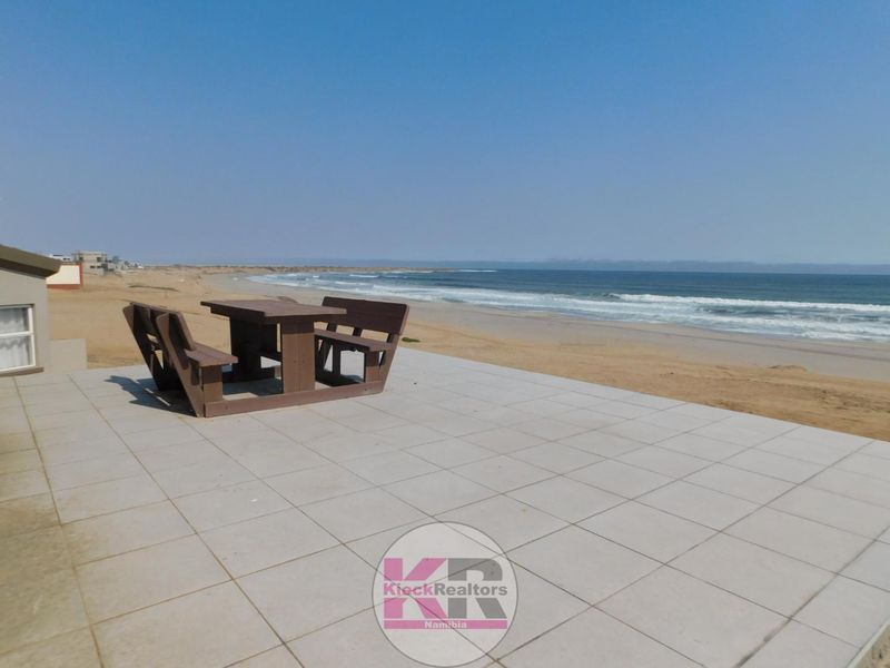 A spacious tiled patio area offering direct access and panoramic views of the beach and ocean.