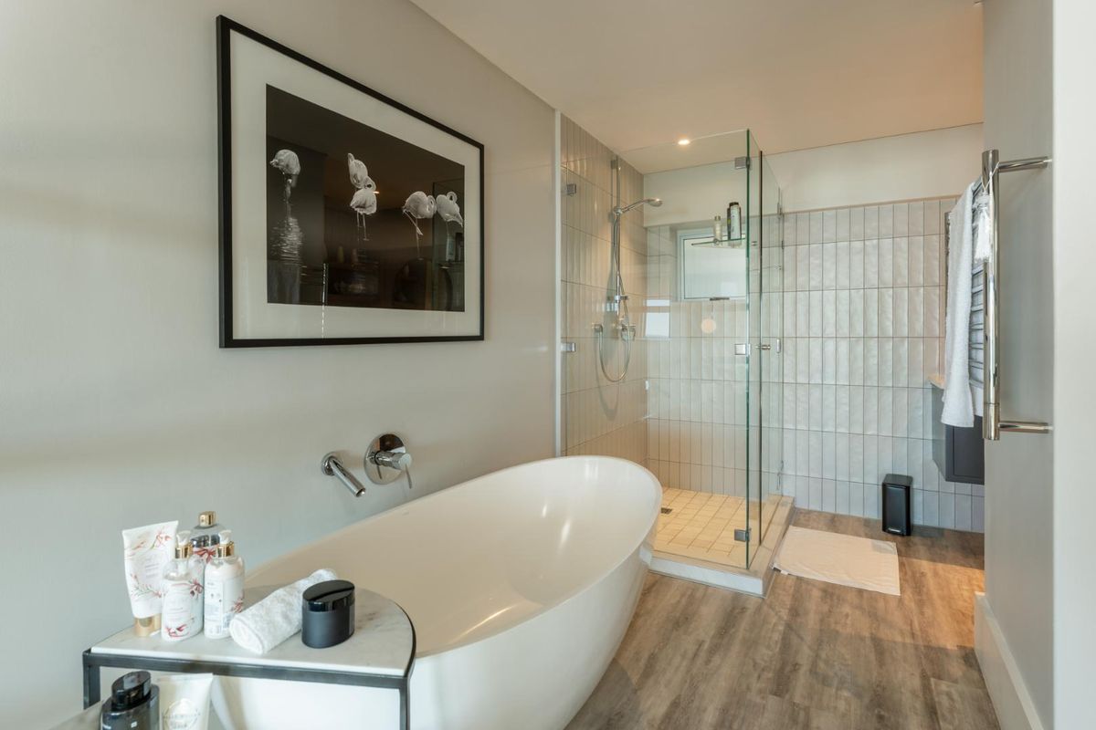 Modern bathroom featuring a freestanding bathtub, a glass-enclosed walk-in shower with tiled walls, and a heated towel rail.