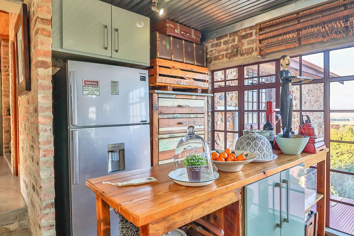 A rustic-style kitchen featuring exposed brick walls, a corrugated metal ceiling, timber countertops, and large steel-framed windows with natural light.