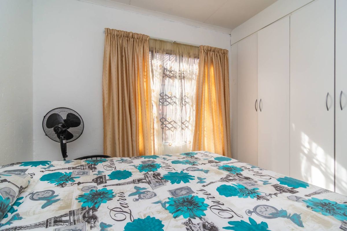 A bedroom featuring built-in cupboards and a window with curtains.