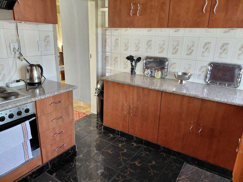A functional kitchen featuring wood-finish cabinetry, granite countertops, a built-in oven and stove, and dark tiled flooring.