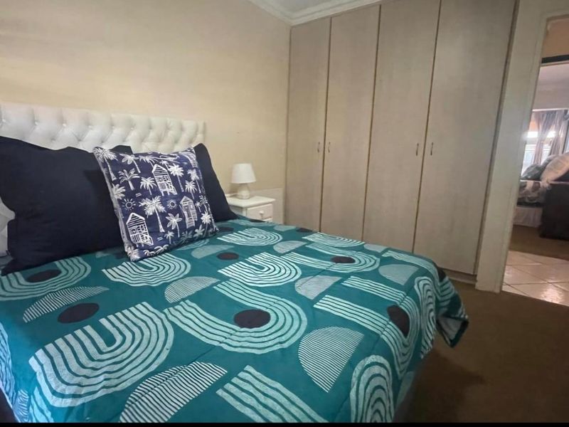 A bedroom featuring built-in cupboards and carpeted flooring, offering a functional space with neutral wall finishes.