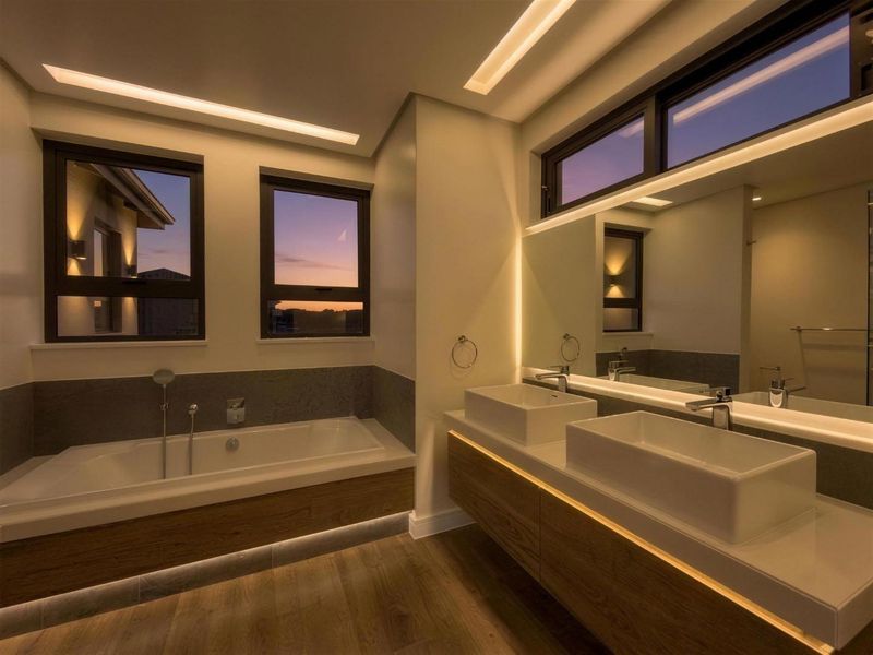 Modern, high-end bathroom featuring a double vanity, built-in bathtub, and sophisticated recessed LED lighting with a clean, contemporary finish.